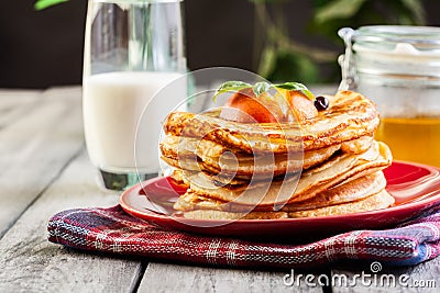 Pancakes with honey, fruit and glass of milk