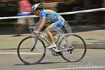 Panning of a beautiful girl riding bicycle in a sunny day, competing for Road Grand Prix event, a high-speed circuit race
