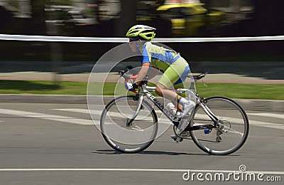 Panning of a very young boy riding bicycle in a sunny day, competing for Road Grand Prix event, a high-speed circuit race