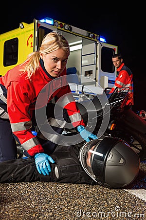 Paramedic assisting motorbike driver at night