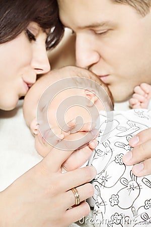 Parents holding newborn baby hand, kissing child
