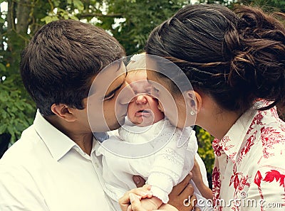 Parents kissing their crying baby