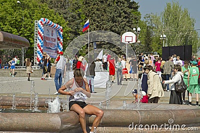Participant of the Volgograd marathon takes plate number with t-shirts sitting at the fountain of Arts