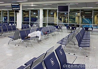 Passenger sleeps on seats in an empty night airport