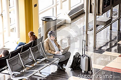 Passengers waiting in front of a bright interior airport window