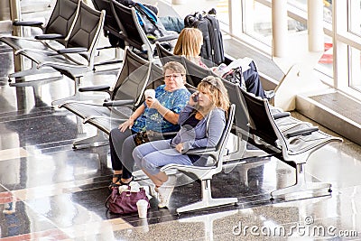 Passengers waiting in front of a bright interior airport window