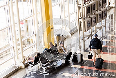 Passengers waiting in front of a bright interior airport window