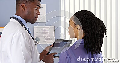 Patient with neck pain talking to male doctor about x ray on tablet