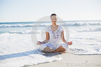 Peaceful pretty woman in lotus position on the beach with wave r
