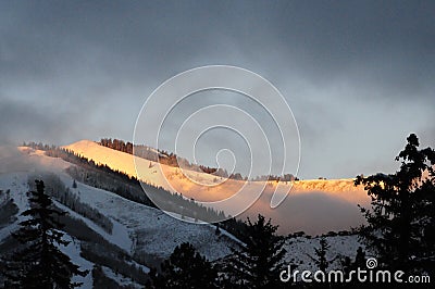 Peaking sun, on snowy mountain.