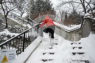 Pedestrian climbs the snow stairs