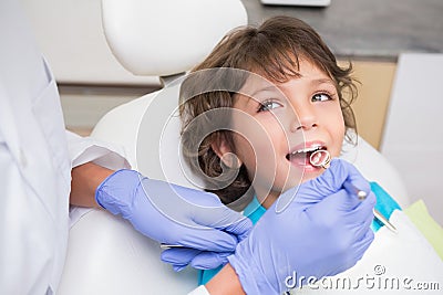 Pediatric dentist examining a little boys teeth in the dentists chair