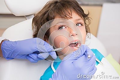 Pediatric dentist examining a little boys teeth in the dentists chair