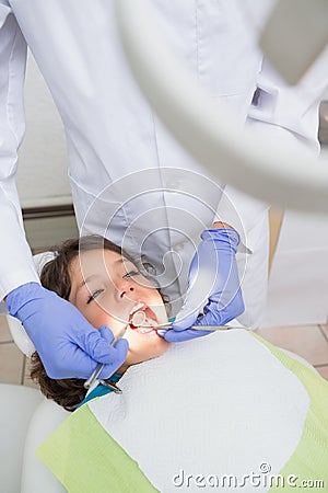 Pediatric dentist examining a little boys teeth in the dentists chair