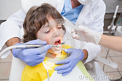 Pediatric dentist examining a little boys teeth in the dentists chair