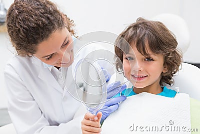 Pediatric dentist showing little boy his teeth in the mirror