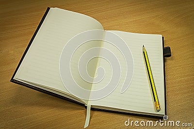 Pencil and notebook with blank page on office table