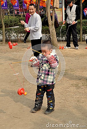 Pengzhou, China: Man and Boy Spinning Tops