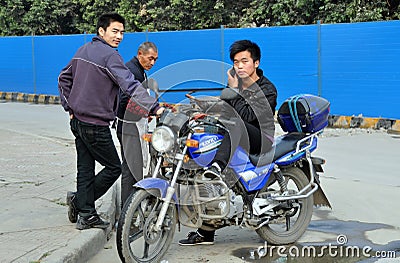 Pengzhou, China: Man on Motorcycle with Cellphone