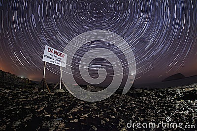 Penmon lighthouse at night with star trails