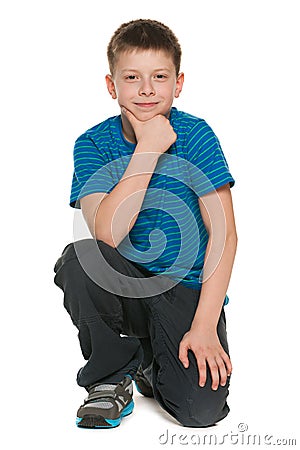 Pensive boy in blue shirt sits on the floor