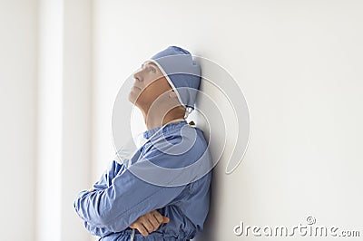 Pensive Surgeon With Arms Crossed Leaning On Wall