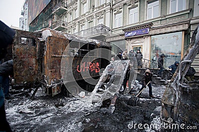 People clean the winter street with ice-covered transport burned in fights with police squads