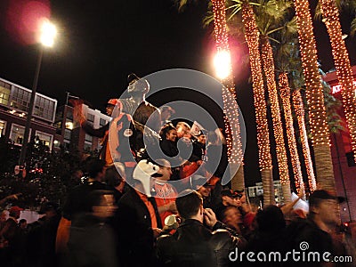 People stand on top Willie Mays statue at night
