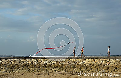 People try to fly a kite on a windy day at the Nusa Dua Beach