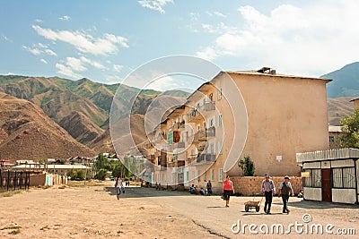 People walk on the street in four-storey house in a small town between the mountains