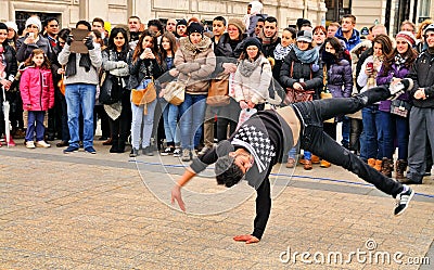 People watch a homeless streetdancer doing breakdance and dance moves in the streets of Paris to earn some money