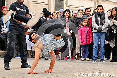 People watch a homeless streetdancer doing breakdance and dance moves in the streets of Paris to earn some money