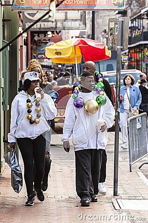 People wearing funny costumes celebrating famous Mardi Gras carnival on the street in French Quarter.