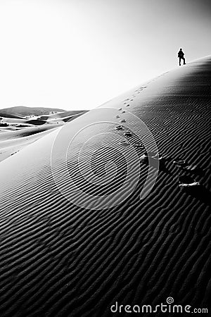 Person standing on top of a high sand dune in Sahara, Morocco