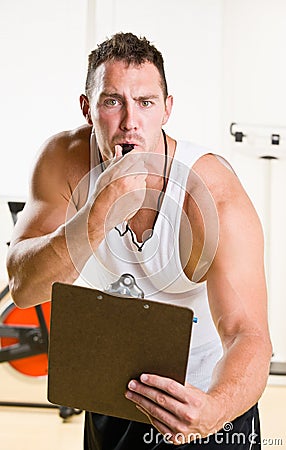 Personal trainer blowing whistle in health club