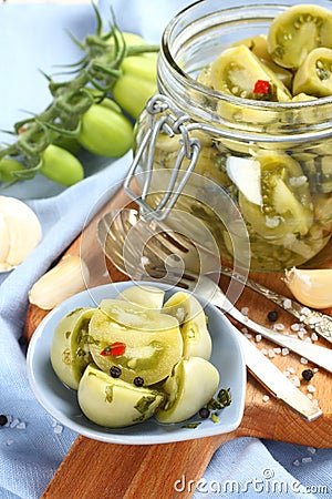 Pickled green tomatoes in blue bowl and in glass jar