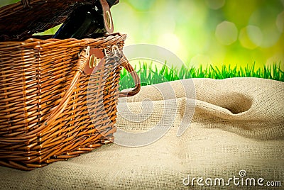 Picnic basket and wine botle on the table with sack cloth