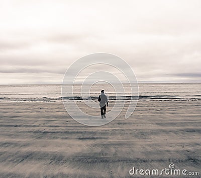 Picture of a man from behind walking on a beach in Scotland (UK)