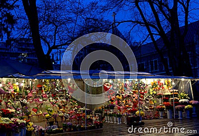 Picturesque flower stalls and a church in the background at night