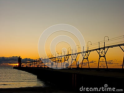 Pier with catwalk and lighthouse at sunset