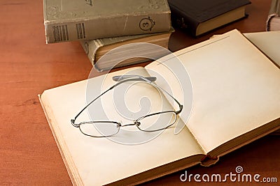 Pile of old books with reading glasses