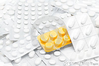 Pills in yellow package over white tablets