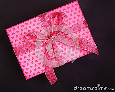 Pink gift box in heart pattern on black