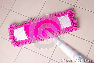 Pink mop cleaning tile floor in bathroom