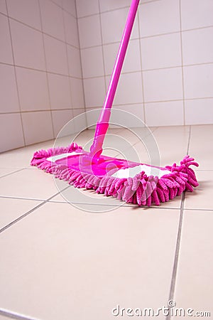 Pink mop cleaning tile floor in bathroom