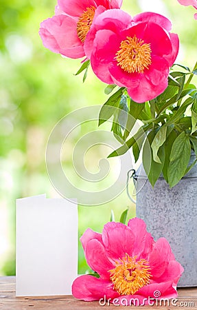 Pink peonies in metal vase and empty card for letter