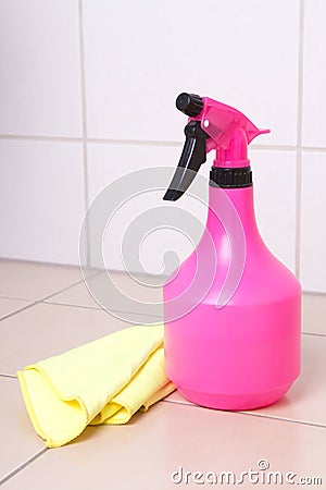 Pink plastic bottle of cleaning product and duster on tiled floo
