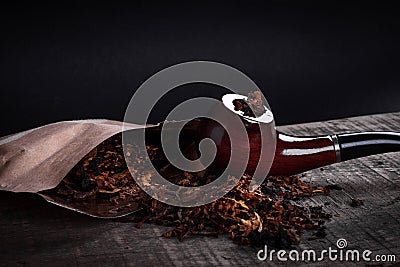 Pipe and tobacco on wooden surface