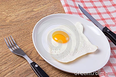 Plate with fried egg, fork and knife on the table