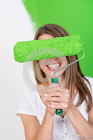 Playful woman hiding behind a paint roller